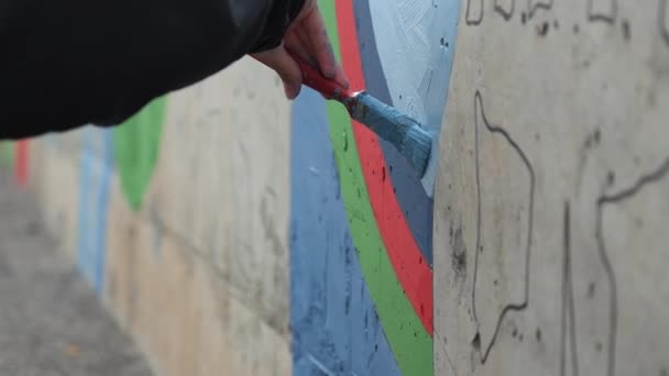 Graffiti művész festmény a falon, külső. Csípés. Közelkép a férfi kéz segítségével ecset és festék díszíteni a falat - Felvétel, videó