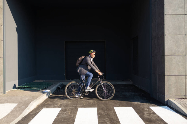 Bonito jovem adulto vestindo terno andando de bicicleta clássica para trabalhar de manhã. Empresário vai trabalhar em bicicleta. Transporte ecológico. - Foto, Imagem