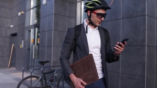 Telefonata cittadina, elegante uomo d'affari in giacca e cravatta e casco che cammina per strada e utilizza il telefono cellulare - Filmati, video