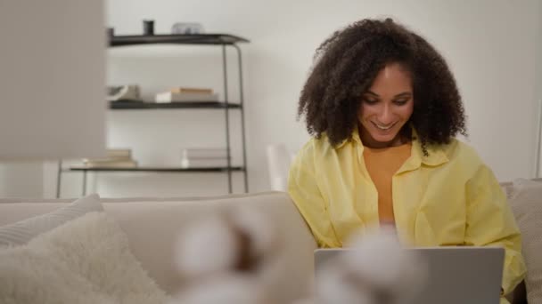 Χαρούμενη χαρούμενη Αφροαμερικανή κοπέλα χαμογελώντας εθνοτική γυναίκα με φορητό υπολογιστή περιήγηση ιστοσελίδα chatting online web surfing νίκη στοίχημα λαχείο επίτευγμα στο σπίτι χαίρονται καλή ευκαιρία ειδήσεις - Πλάνα, βίντεο