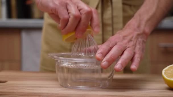 A mão espreme o suco de limão de meio limão em um espremedor de frutas cítrico claro.  - Filmagem, Vídeo