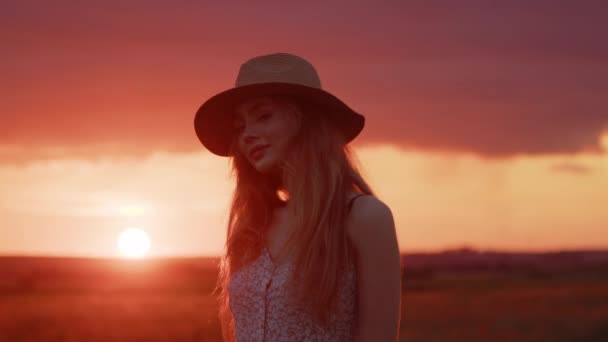 Portrét mladé dívky na pozadí krásného letního západu slunce na poli - Záběry, video