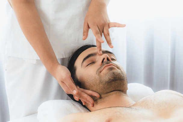 Uomo caucasico godendo rilassante anti-stress massaggio alla testa e coccole bellezza del viso svago della pelle in dayspa luce moderna ambiente al resort di lusso o salone spa dell'hotel. Silenzioso - Foto, immagini