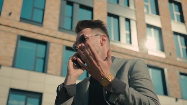 Güneş gözlüklü kızgın işadamı telefonda sinirli adam girişimci lider iş sorunlarını dışarıda ofis yakınlarındaki akıllı telefonla çözüyor sinirli müşteri krizini tartışıyor - Video, Çekim