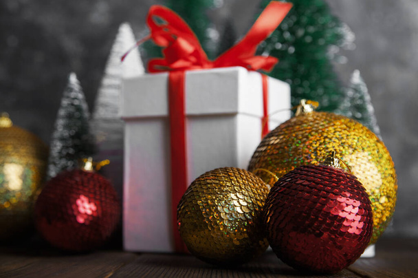 Tarjeta de felicitación navideña sobre fondo oscuro. Caja con regalo, bolas de Navidad, árboles y espacio para copiar. - Foto, Imagen