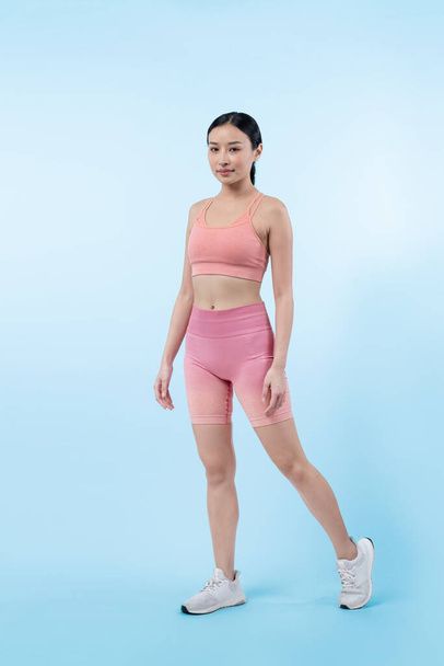 Spor giyim portresindeki tüm vücut Asyalı kadın gülümsüyor ve neşeli bir jest yapıyor. Çekici bir kızla egzersiz yapmak sağlıklı yaşam tarzını sürdürmeye yöneliktir. İzole edilmiş arka plan Vigorous - Fotoğraf, Görsel
