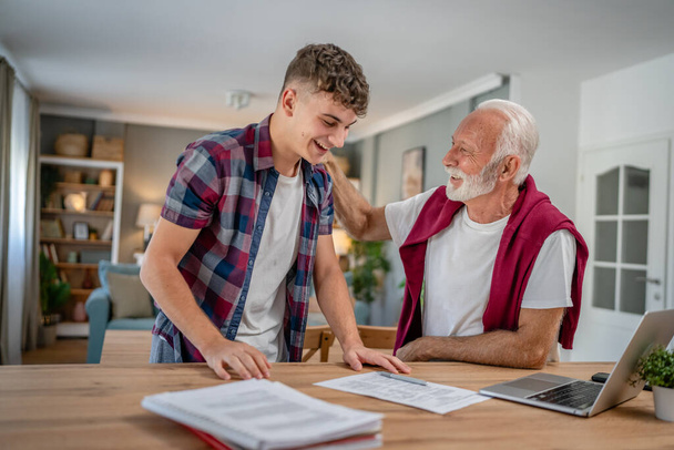 One student teenage caucasian man teen study learn with help of his tutor professor or grandfather senior man at home having private lesson to prepare for exam education concept real people copy space - Photo, Image