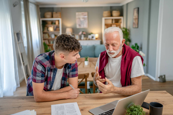 One student teenage caucasian man teen study learn with help of his tutor professor or grandfather senior man at home having private lesson to prepare for exam education concept real people copy space - Photo, Image