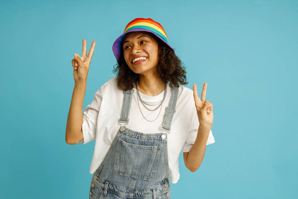 Stílusos boldog nő bemutató jel béke és nézi oldalán álló kék stúdió háttér  - Fotó, kép