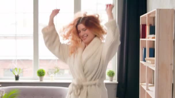 Kaukasisch gelukkig actief meisje dansen springen bewegend luisteren naar muziek in de ochtend vrouw dans springen in slaapkamer vreugde beweging verplaatsen naar lied weekend vakantie in luxe hotelkamer vrolijke vrouw plezier hebben - Video