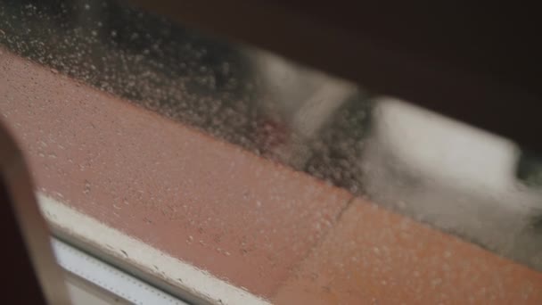 雨に覆われた窓と半開きの盲目を通して,駐車された車はぼやけの中に見えます - 映像、動画