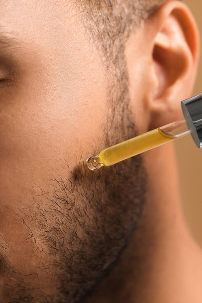 Man applying cosmetic serum onto face, closeup - Valokuva, kuva