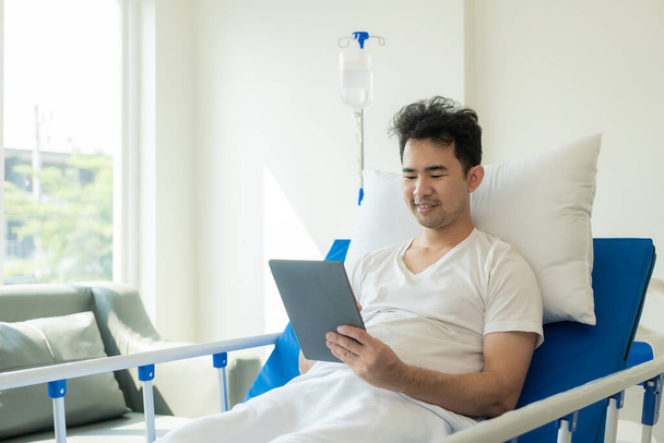 Jeune homme asiatique, patient allongé sur un lit d'hôpital, en traitement dans une clinique médicale. Concept d'assurance maladie ou hospitalité - Photo, image