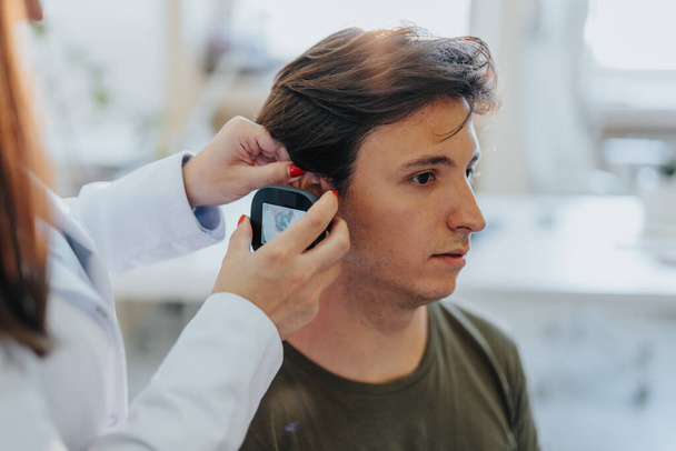 Лікар перевіряє вухо пацієнта за допомогою відео-отоскопа. Крупним планом фото. - Фото, зображення