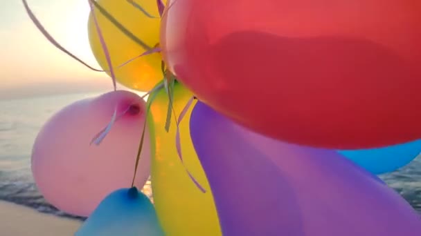 Muitas bolas infláveis coloridas no fundo do mar ao amanhecer e ao pôr do sol. Pessoa brincando com balões de ar multicoloridos na mão perto do mar ao nascer do sol. Sol brilhando através de bolas. Diversão do entretenimento - Filmagem, Vídeo