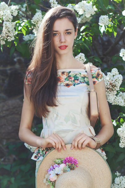 Beautiful young girl model posing near blooming lilacs at spring - Фото, зображення