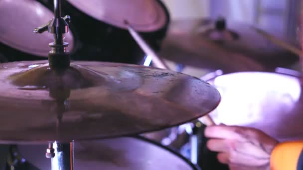 Mani maschili di batterista professionista che tiene bacchette di legno e colpisce sulla batteria durante il concerto rock indoor. Primo piano del processo di esecuzione di uno strumento musicale. Vista laterale rallentatore. - Filmati, video