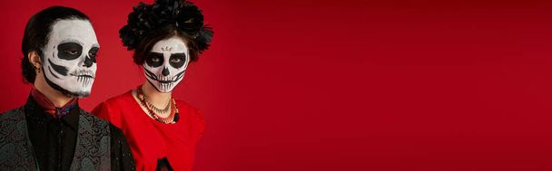 Діа де лос мюарс пара, жінка в моторошному макіяжі черепа і чорний вінок біля чоловіка на червоному, банер - Фото, зображення