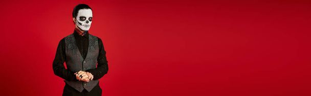 elegantní muž v strašidelné dia de los muertos cukr lebka make-up při pohledu na kameru na červenou, banner - Fotografie, Obrázek
