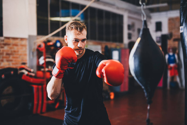 Μπόξερ κάνει προπόνηση πυγμαχίας με punchbag σε ένα γυμναστήριο - Φωτογραφία, εικόνα