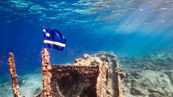 Épave de navire "Tugboat" dans les eaux peu profondes du récif corallien dans la mer des Caraïbes avec drapeau Curaçao, vue sur la surface et les rayons de soleil - Photo, image