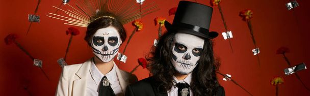 día de los muertos, pareja en maquillaje aterrador, sombrero de copa y corona sobre fondo rojo con flores, estandarte - Foto, Imagen