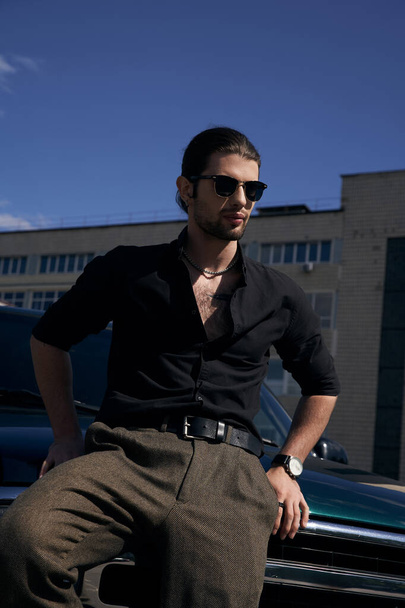 vertical shot of elegant man with beard and sunglasses wearing black casual attire, sexy driver - Photo, Image