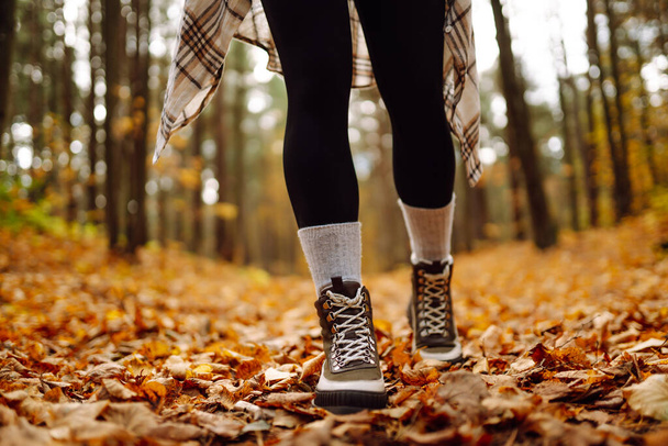 Autumn mood. Close-up of female legs in hiking boots on autumn leaves in the park. The concept of nature, relaxation, walking. - Foto, Imagem