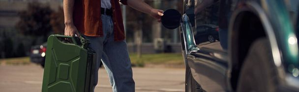 vista ritagliata del giovane in camicia marrone elegante con jeans rifornimento della sua auto con benzina, banner - Foto, immagini