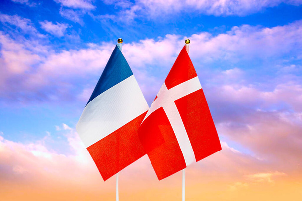 Bandeiras nacionais da França e Dinamarca contra o céu ao pôr-do-sol. Bandeiras. - Foto, Imagem