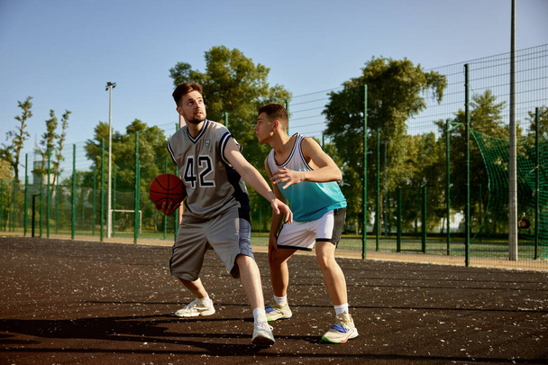 ストリートコートでバスケットボールをするアクティブな男性. 週末の友人のためのスポーツと趣味のレクリエーション - 写真・画像