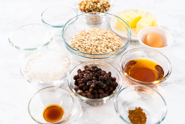 Ingredientes medidos en cuencos de vidrio para hornear galletas de avena blandas con pasas de uva. - Foto, Imagen