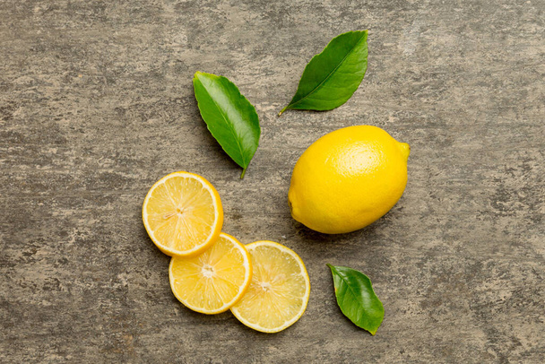 Muchos limones maduros frescos con hojas verdes sobre fondo de color, vista superior, espacio para el texto. - Foto, Imagen