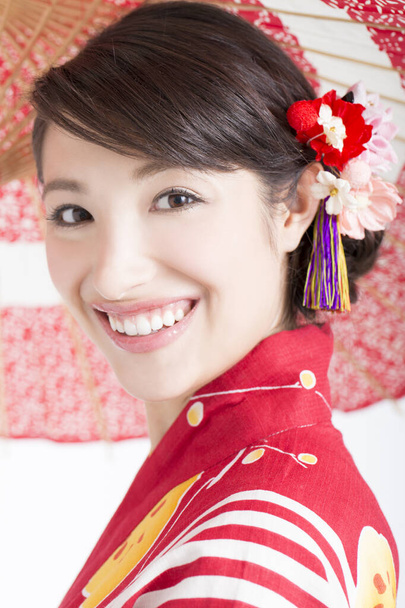 smiling Asian woman in traditional red kimono with a white background - Foto, immagini