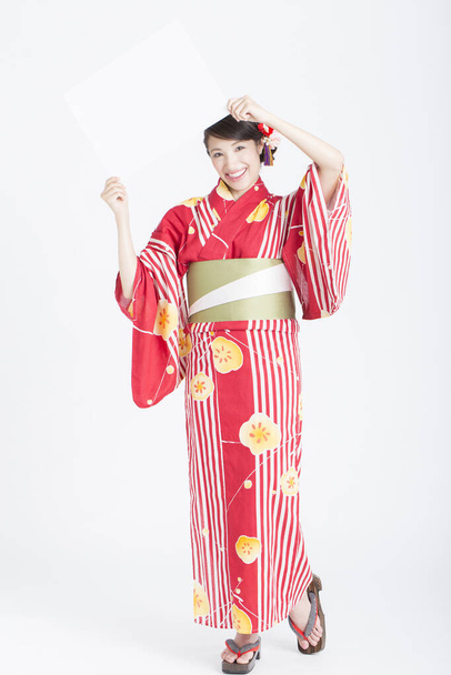 young Asian woman in traditional kimono holding blank card - Foto, Bild