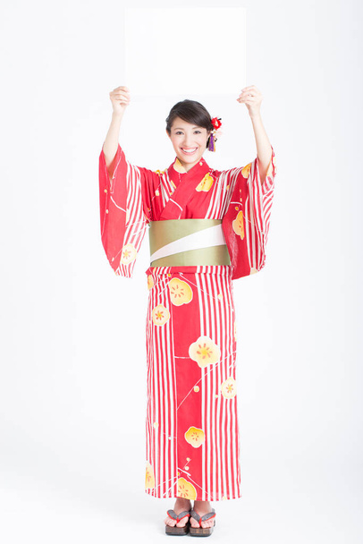 young Asian in traditional kimono holding blank card - Fotografie, Obrázek