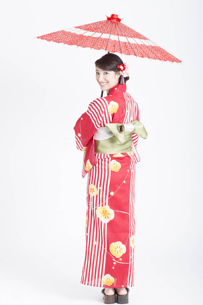 portrait of beautiful japanese woman in kimono with red umbrella  - Фото, изображение