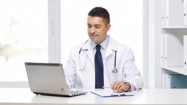 doctor feliz con el ordenador portátil y portapapeles en el hospital
 - Imágenes, Vídeo