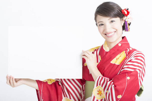 young woman in traditional kimono holding blank card - 写真・画像