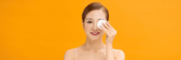 Young healthy Asian woman with beautiful clear skin holding cotton pad on banner background - Photo, Image