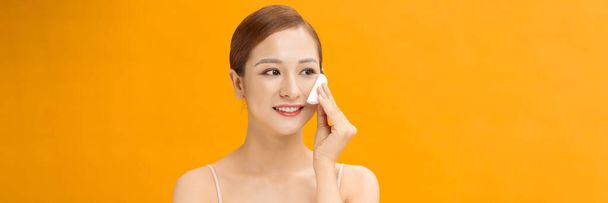 Young healthy asian woman with beautiful clear skin holding cotton pad on banner background - Photo, Image