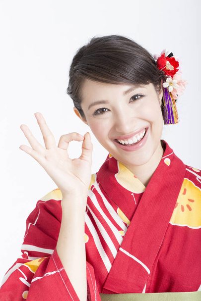 asian woman wearing a traditional kimono showing ok gesture with fingers. - Foto, imagen