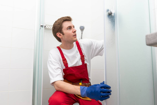Pracownicy instalują uszczelkę silikonową na szklanych drzwiach kabiny prysznicowej - Zdjęcie, obraz