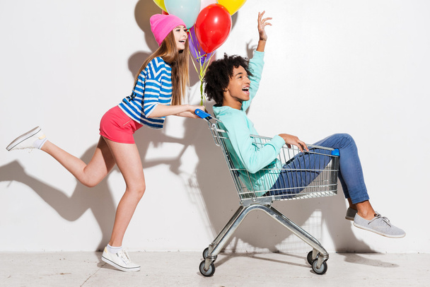 Girl carrying his boyfriend in shopping cart - Foto, afbeelding