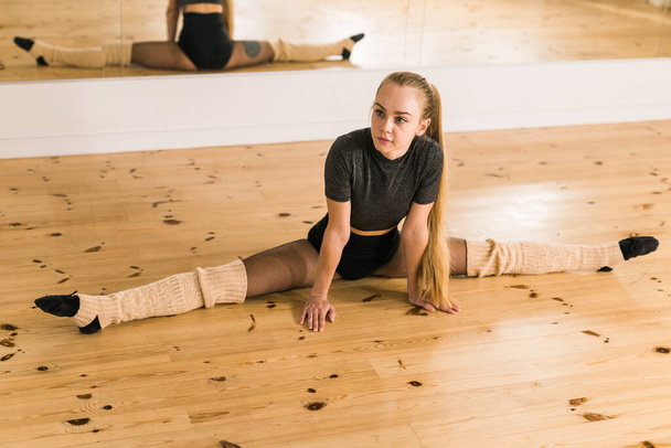 Young woman ballerina stretching and training at barre in dance studio - ballet and dancer - Фото, зображення