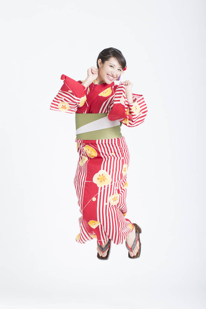 портрет красивой молодой азиатки в традиционном красном кимоно на белом фоне студии - Фото, изображение