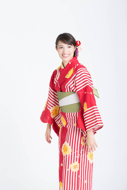 白いスタジオの背景にポーズする伝統的な赤い着物の美しい若いアジアの女性の肖像画 - 写真・画像