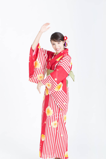 portrait of beautiful young Asian woman in traditional red kimono posing on white studio background - Foto, Imagem