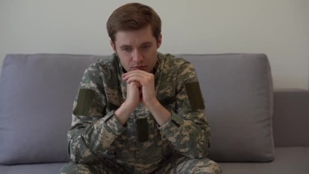 Joven soldado nervioso deprimido usando camuflaje sentado en la oficina del psicoterapeuta y escuchando, obtener ayuda profesional, cámara lenta, espacio vacío - Metraje, vídeo