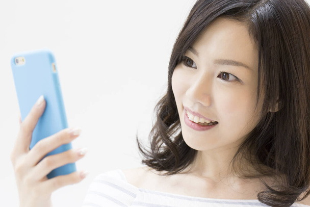Studio shot  of beautiful Japanese woman using  smartphone  on white background  - Фото, зображення
